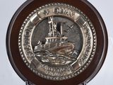 un plateau en argent orné d'un bateau, posé sur un socle