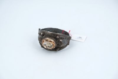 a silver ring with a clock on it on a white surface
