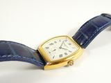 a watch with a blue strap on it on a white surface