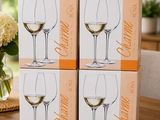 three boxes of wine glasses sitting on a table with flowers in the background