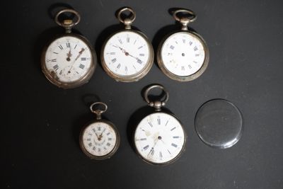 plusieurs montres de poche de différents types posées sur une table, à côté d'une loupe