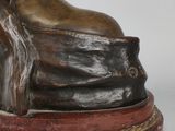 a bronze statue of a woman sitting on a rock with her head resting on her hands