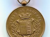 an image of a gold medal with a crown on top of it