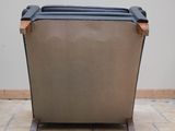 the back of a brown leather chair on a tile floor