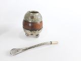 un vase en argent et en bois et une cuillère posés sur une surface blanche