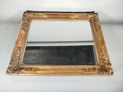 un miroir avec un cadre doré posé sur une surface blanche