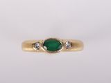 gros plan d'une bague en or avec une pierre verte