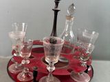 des bouteilles et des verres posés sur un plateau, sur une table où se trouve une lampe