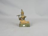 bronze figurine of a man playing a flute on a green base