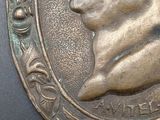 a close up of a bronze medallion with a man ' s face