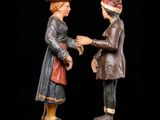 two wooden figures of a man and a woman shaking hands