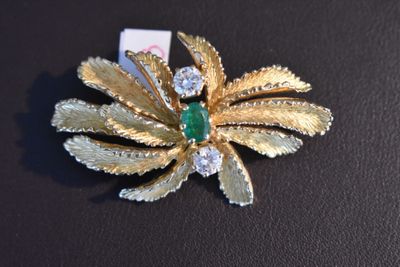a gold brooch with a green stone in it