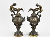 pair of bronze vases with figures on top of them