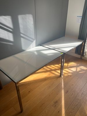 une table blanche avec un plateau en verre, posée sur un parquet en bois massif
