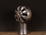 a silver sculpture of a lion head on a wooden table