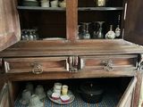 an old wooden cabinet with many dishes and cups on it