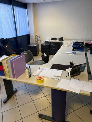 un bureau encombré de papiers, dans une pièce