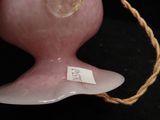 a pink vase with a rope around it on a black surface