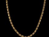 un collier à chaîne en or aux maillons carrés sur fond noir