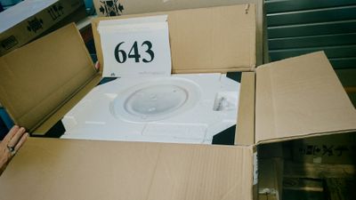 des toilettes blanches dans un carton sur lequel est accrochée une pancarte