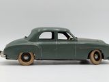 a green toy car that is sitting on a white surface