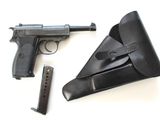 un pistolet, un étui et un chargeur posés sur une surface blanche