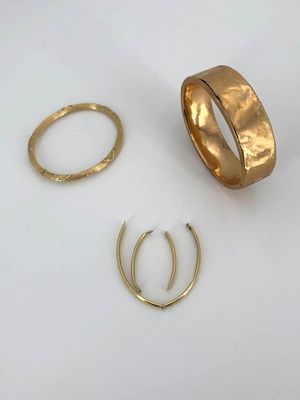 three gold rings and two gold hoops on a white surface