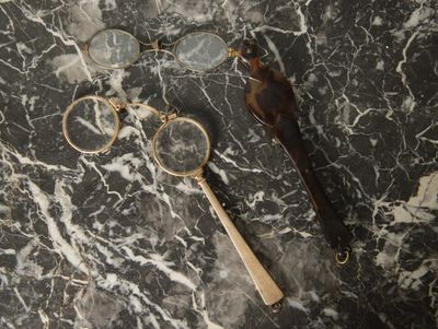 une paire de lunettes et une loupe posées sur une table en marbre