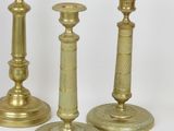 three brass candlesticks on a white surface with a white background