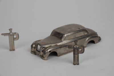 une petite voiture argentée et une clé posées sur une surface blanche
