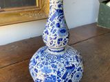 a blue and white vase sitting on a table in front of a painting