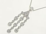 un gros plan d'un collier en diamants posé sur une surface blanche