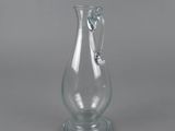 clear glass vase with a handle on a gray background