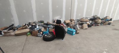 un chat assis par terre à côté d'un tas de vieilleries