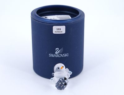 a small glass penguin sitting in front of a blue container