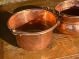 deux casseroles en cuivre posées l'une à côté de l'autre sur une table en bois