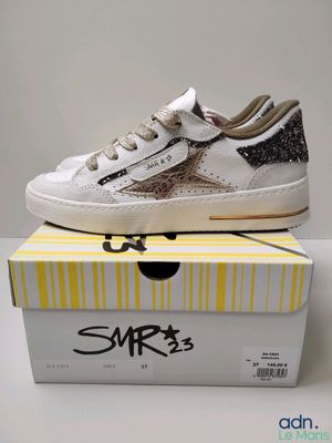 a pair of white sneakers with black and gold glitters on them
