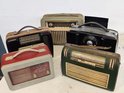 Plusieurs radios à l'ancienne sont alignées sur une table