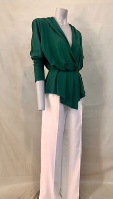 Le mannequin porte un haut vert et un pantalon blanc.