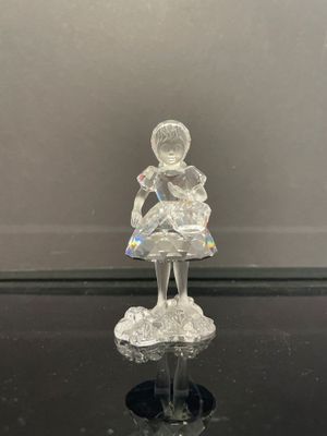une figurine en verre représentant une petite fille assise sur une table