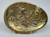 an antique gold plate with a bird and flowers on it