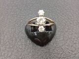 a close up of a diamond and gold ring on a black stone