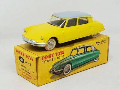 yellow toy car sitting on top of a box on a white surface