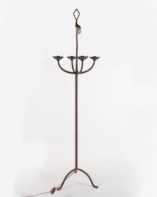 a metal floor lamp with three candles on a stand on a white background