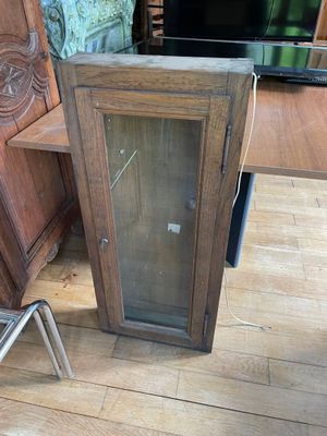 a wooden cabinet with a glass door and a chair in front of it