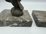 two statues of a bird sitting on top of a marble block