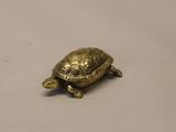 une petite tortue en or posée sur une table