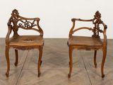 une paire de chaises anciennes en bois sculpté posées sur un parquet dans une pièce