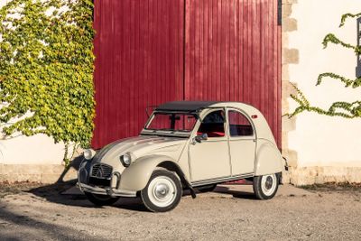 une petite voiture beige garée devant une porte rouge