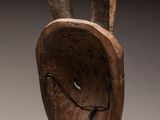 sculpture of a wooden head with horns on a metal stand